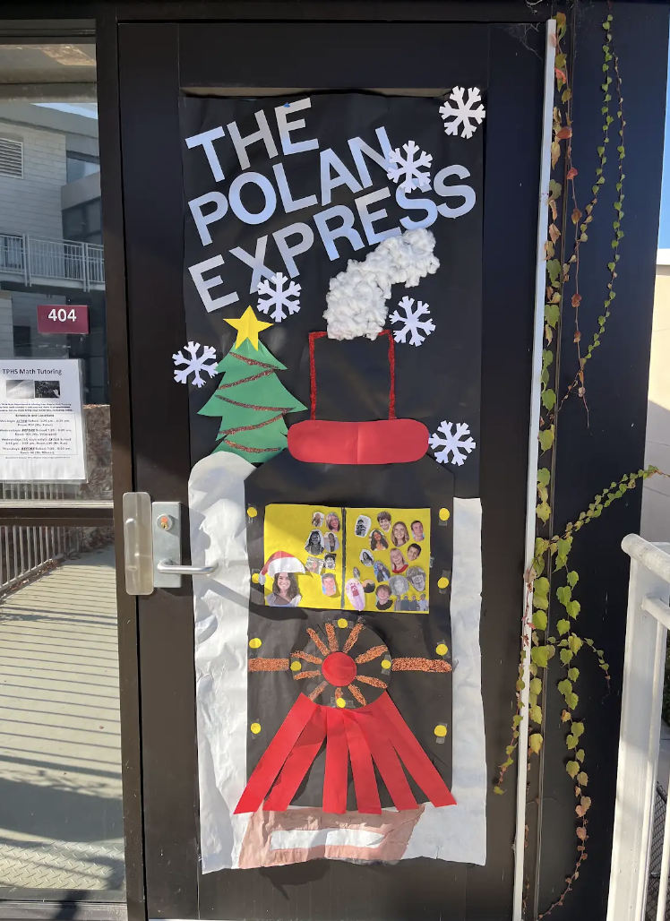 Math teacher Annie Polan's door is creatively decorated with a pun for the movie 'Polar Express.' The door is adorned with the polar express and other paper additions.